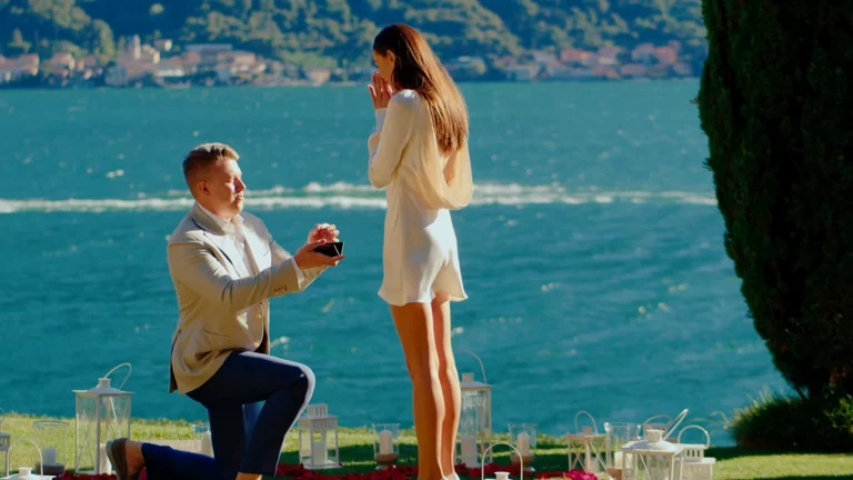 Pavel on one knee proposing to Alina on the lawn of Villa La Cassinella overlooking Lake Como